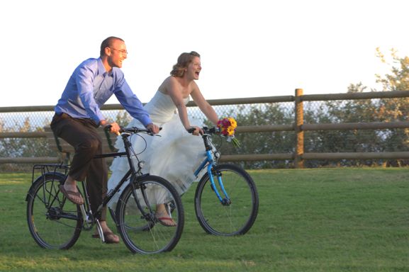 Steven and Taressa riding their bikes in their wedding clothes