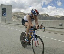 Stacia on her american flag time trial bike crossing the top of a dam at high speed
