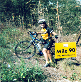 Heather S holding her Rodriguez bike at the mile 90 marker on a ride